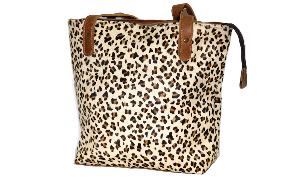 Leopard print tote bag with brown leather straps on a white background